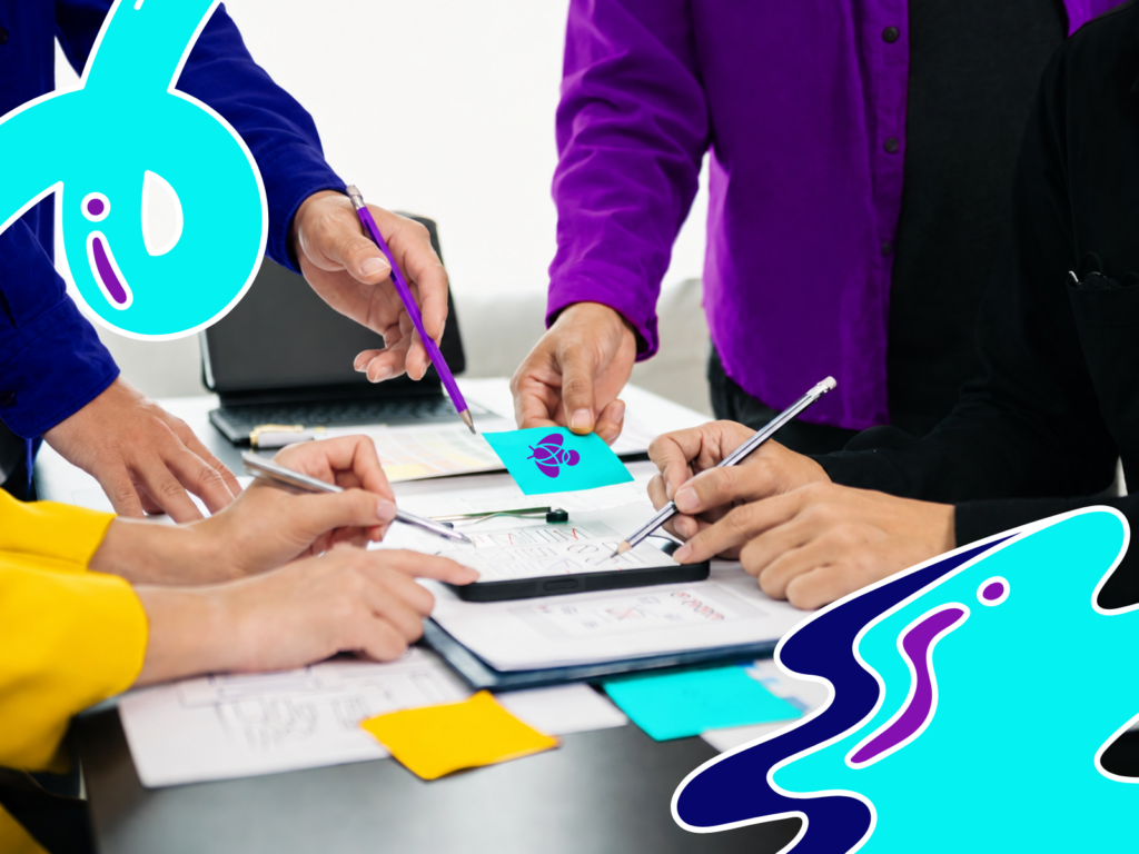 Cuatro personas trabajan juntas sobre una mesa con bocetos, lápices y notas adhesivas